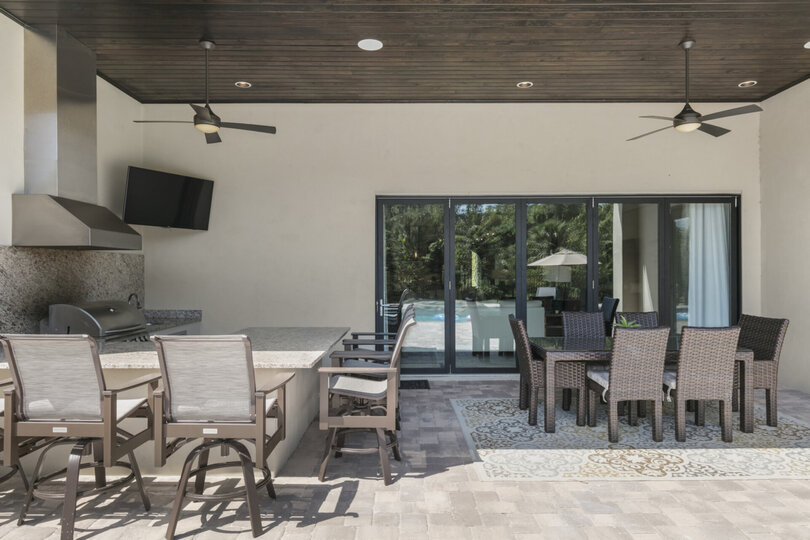 The covered lanai features a summer kitchen, 50-inch TV, and outdoor dining table