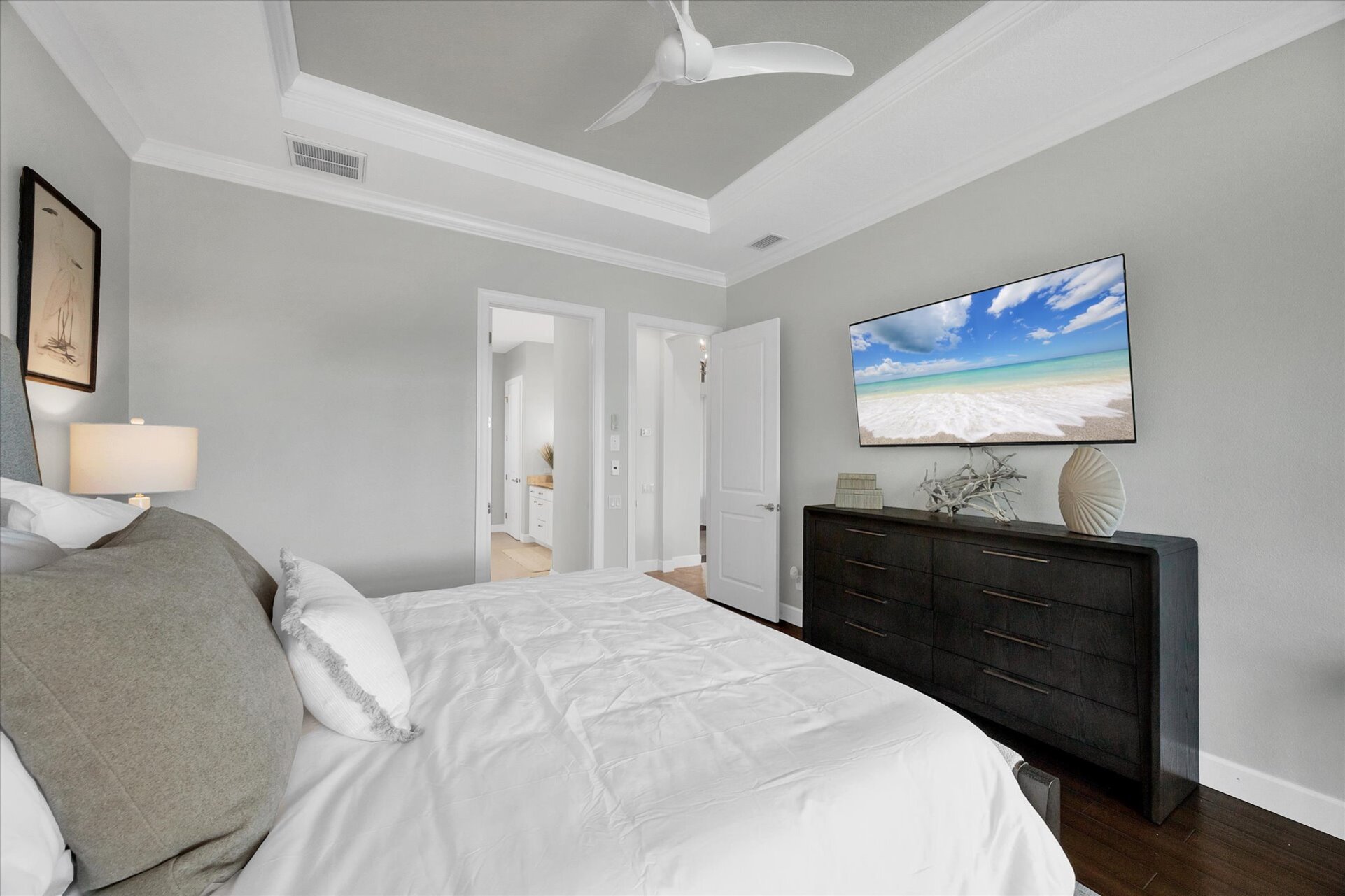 Primary bedroom features king bed, attached bathroom, desk & chair, 65-inch Smart TV, and beautiful view of pool and canal